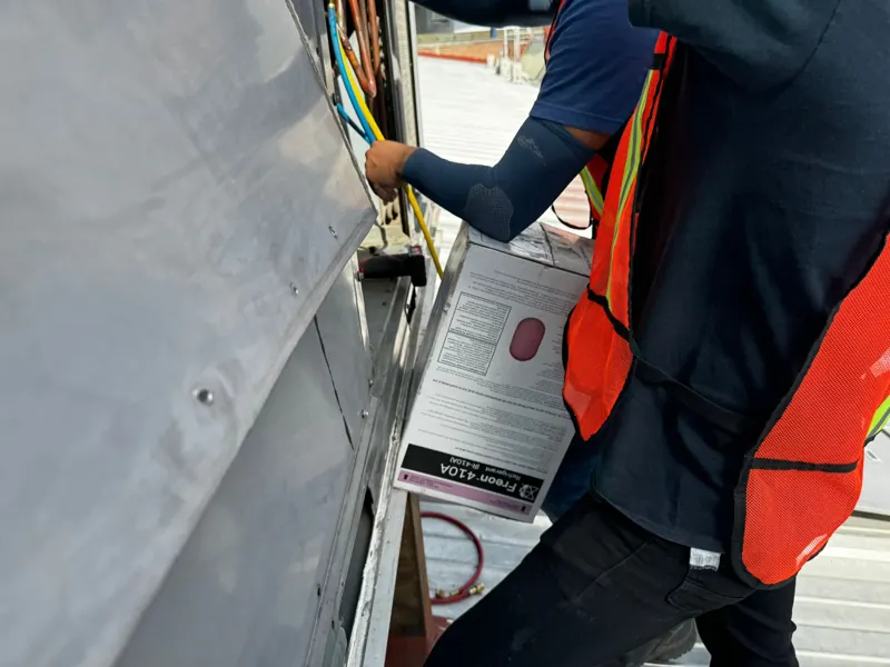 Técnico con chaleco de seguridad cargando refrigerante R-410A