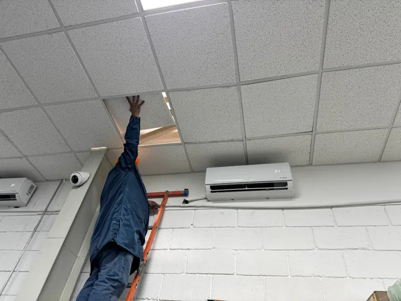 Técnico trabajando en plafón junto a cámara de videovigilancia